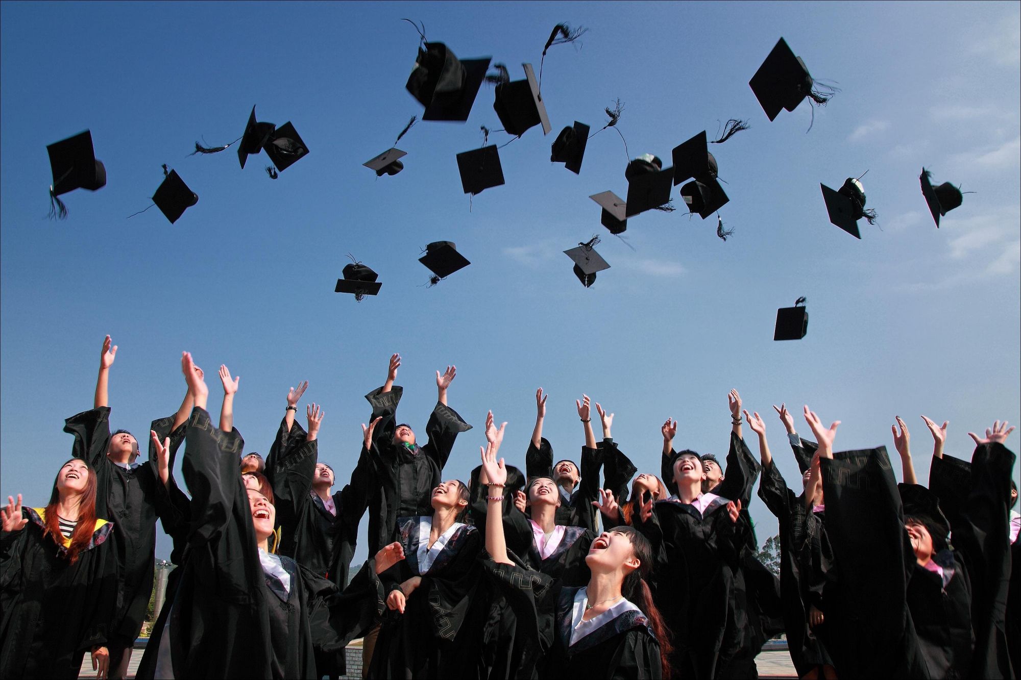 A group of students throwing their graduation hats in the air.