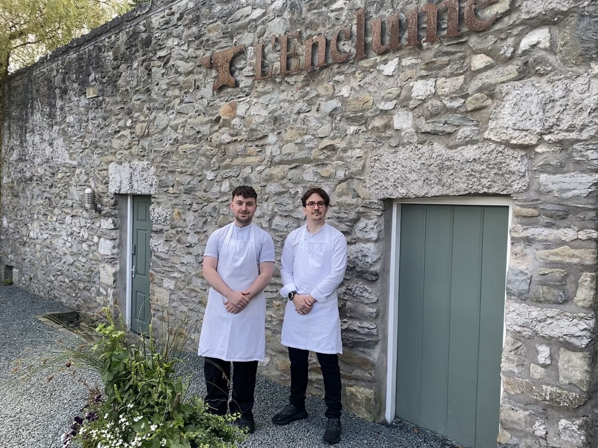 Lewis and colleague standing outside restaurant under sign
