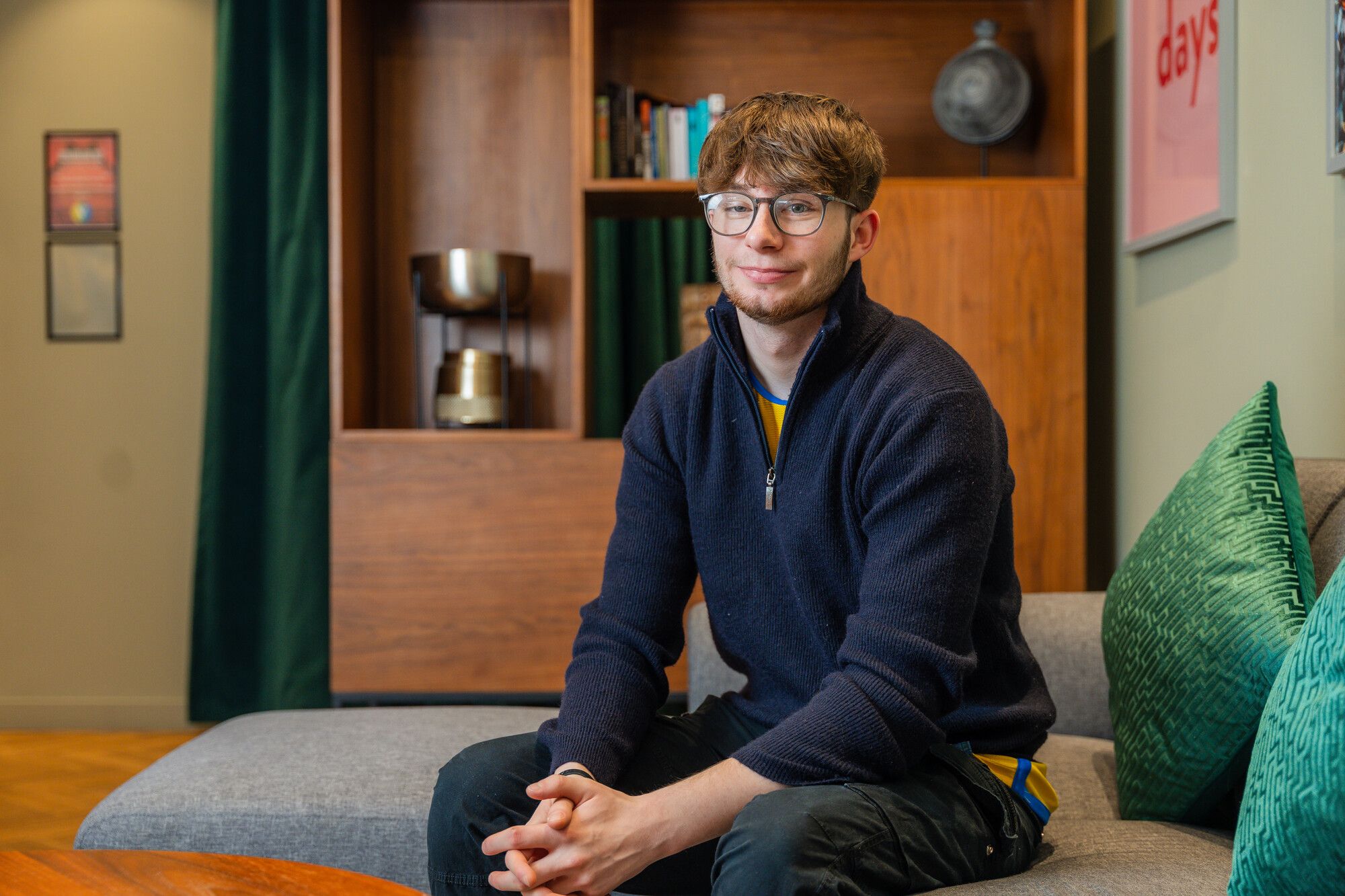 Male student sitting on a sofa in student accommodation.