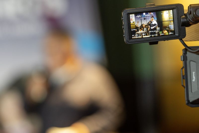 Landscape image showcasing a camera set up recording the Ardmore event at the Academy Restaurant with the focus being the camera screen and the background being out of focus.