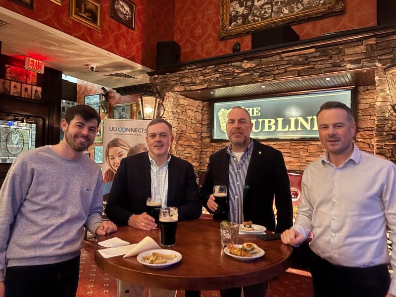 four men standing at a table and eating food