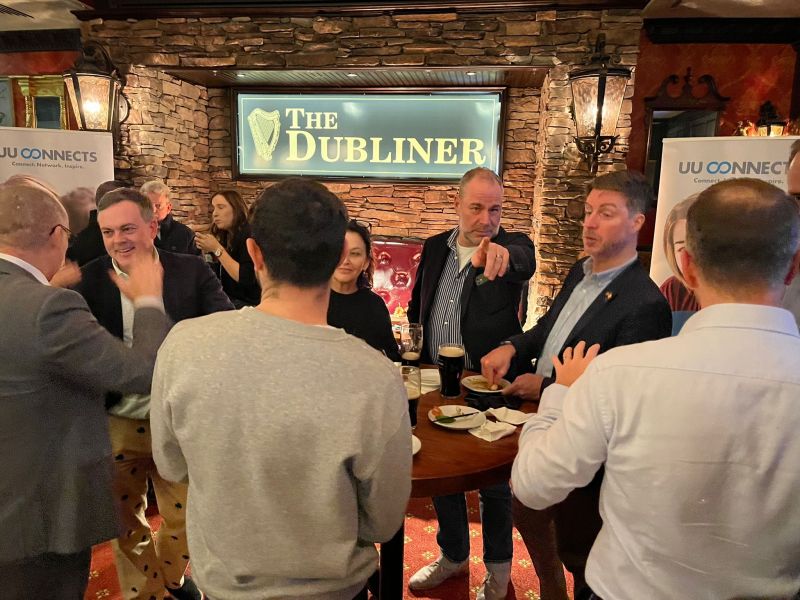 group of men around a round table enjoying drinks and talking