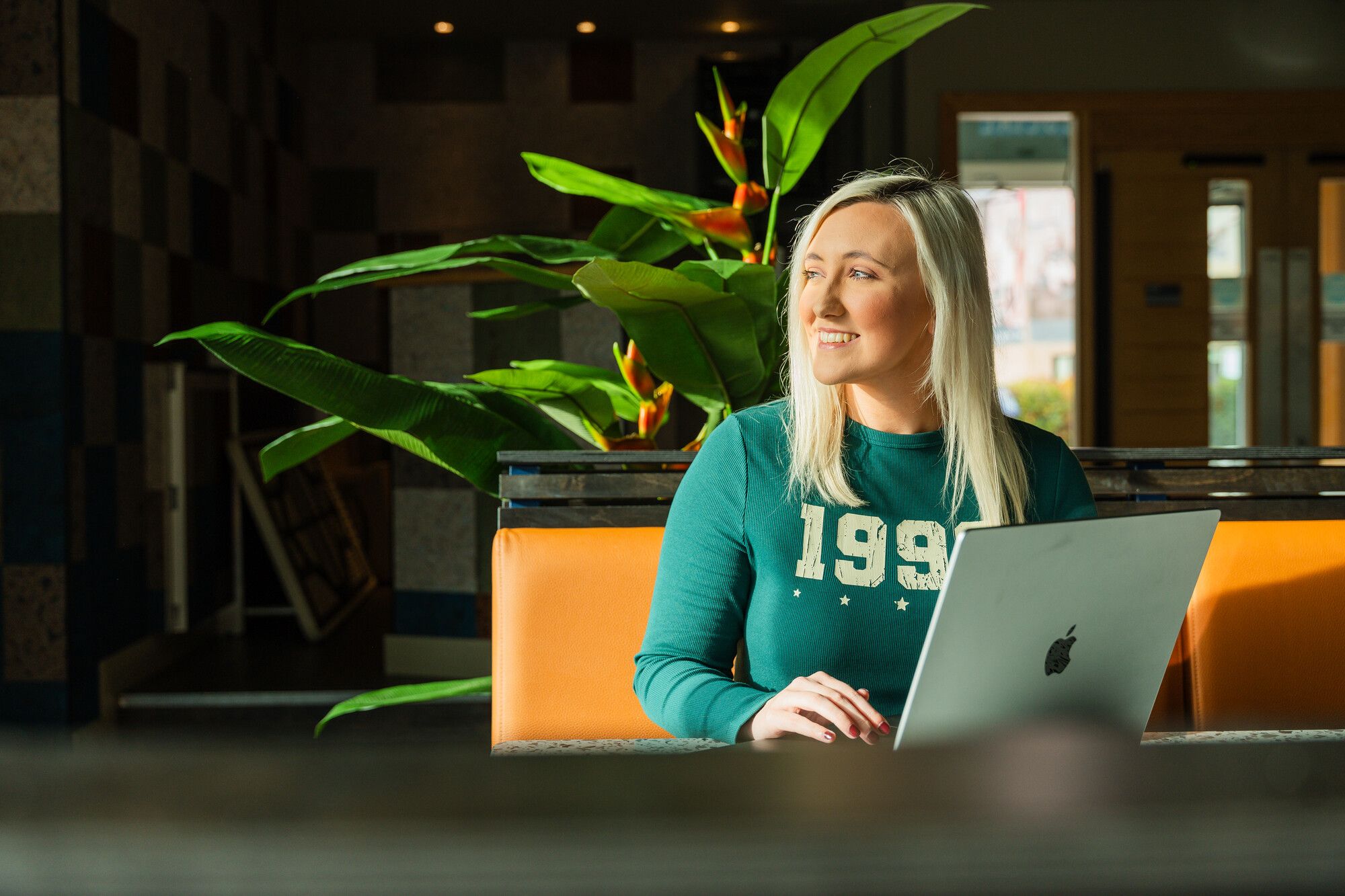 Female student sitting with a laptop looking out a window