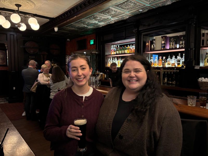 two women posing with drinks in a bar