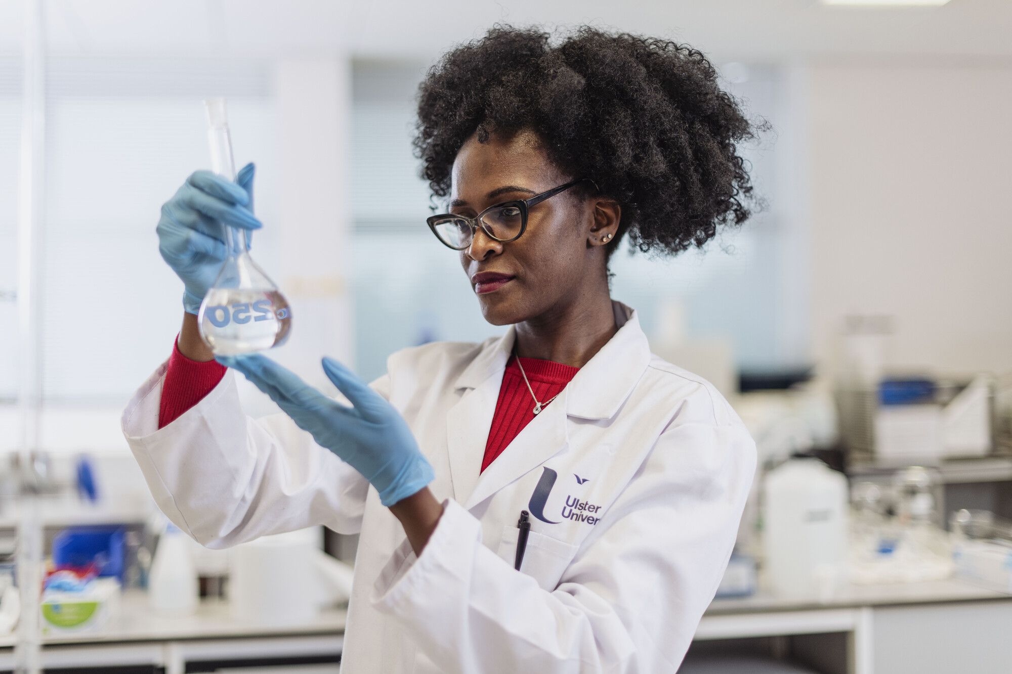 Female PhD Researcher wearing a white coat and holding a test tube