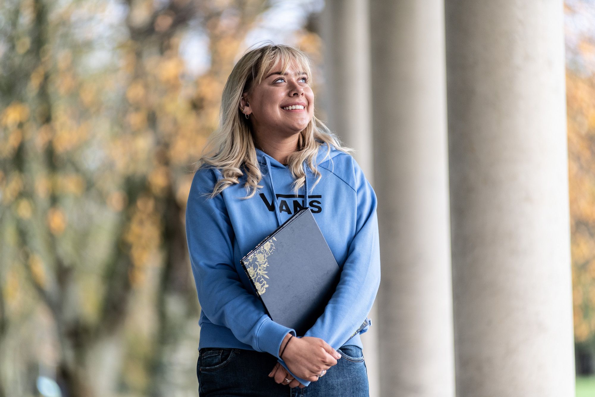woman standing with a book in a blue hoodie