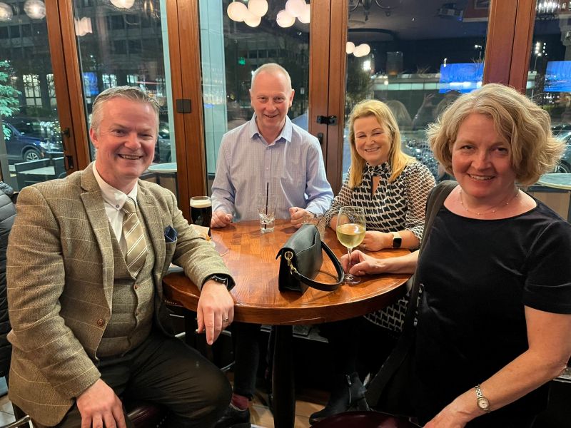 two males and two females with drinks sitting at a round table