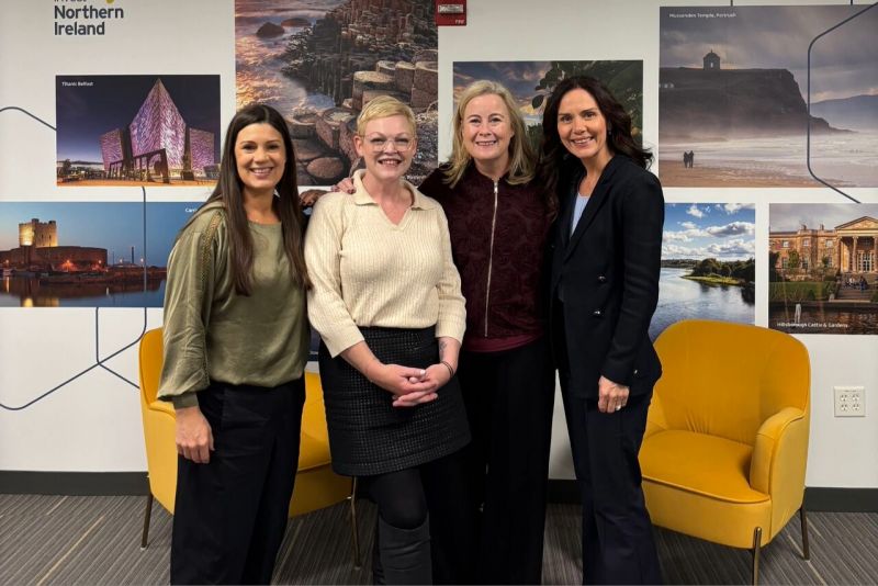 four women with arms around eachother standing in an office