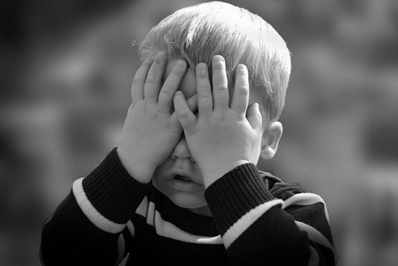 young boy covering face