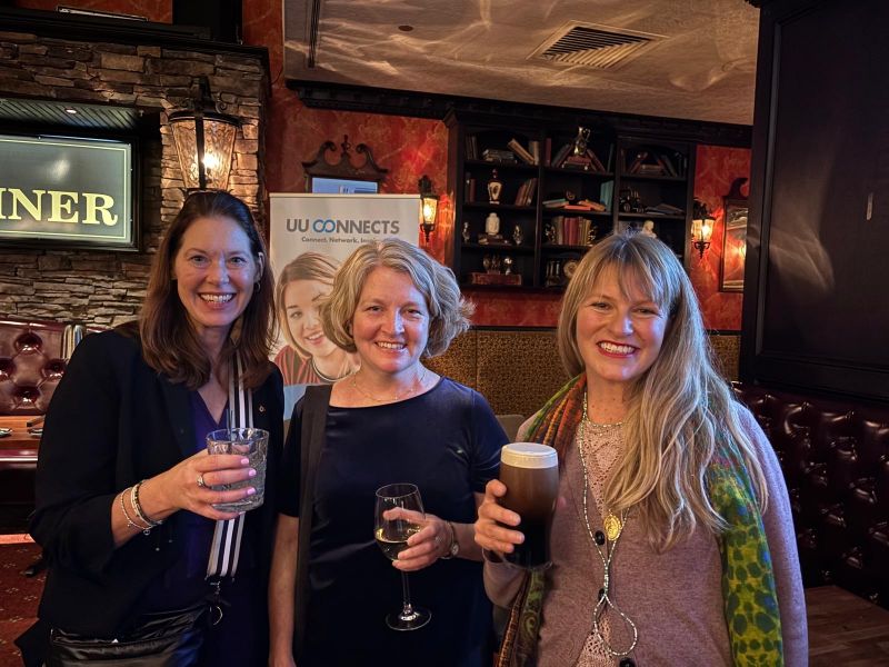 three women posing with drinks in a bar