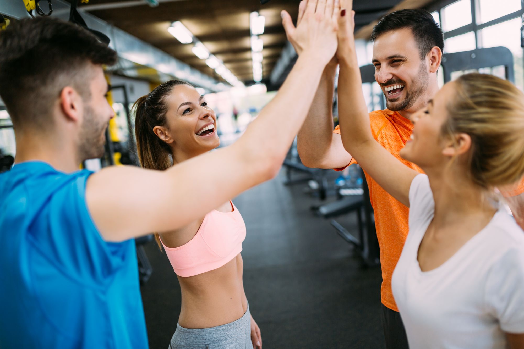 smiling men and woman giving high five at gym