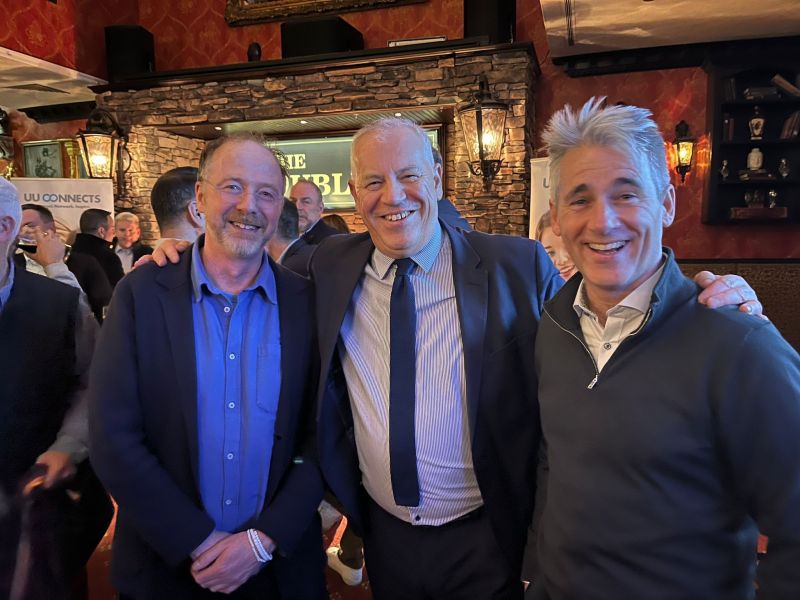 three men with their arms around eachothers shoulders in a bar