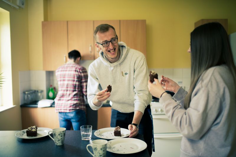 Men and women eating cake in the kitchen