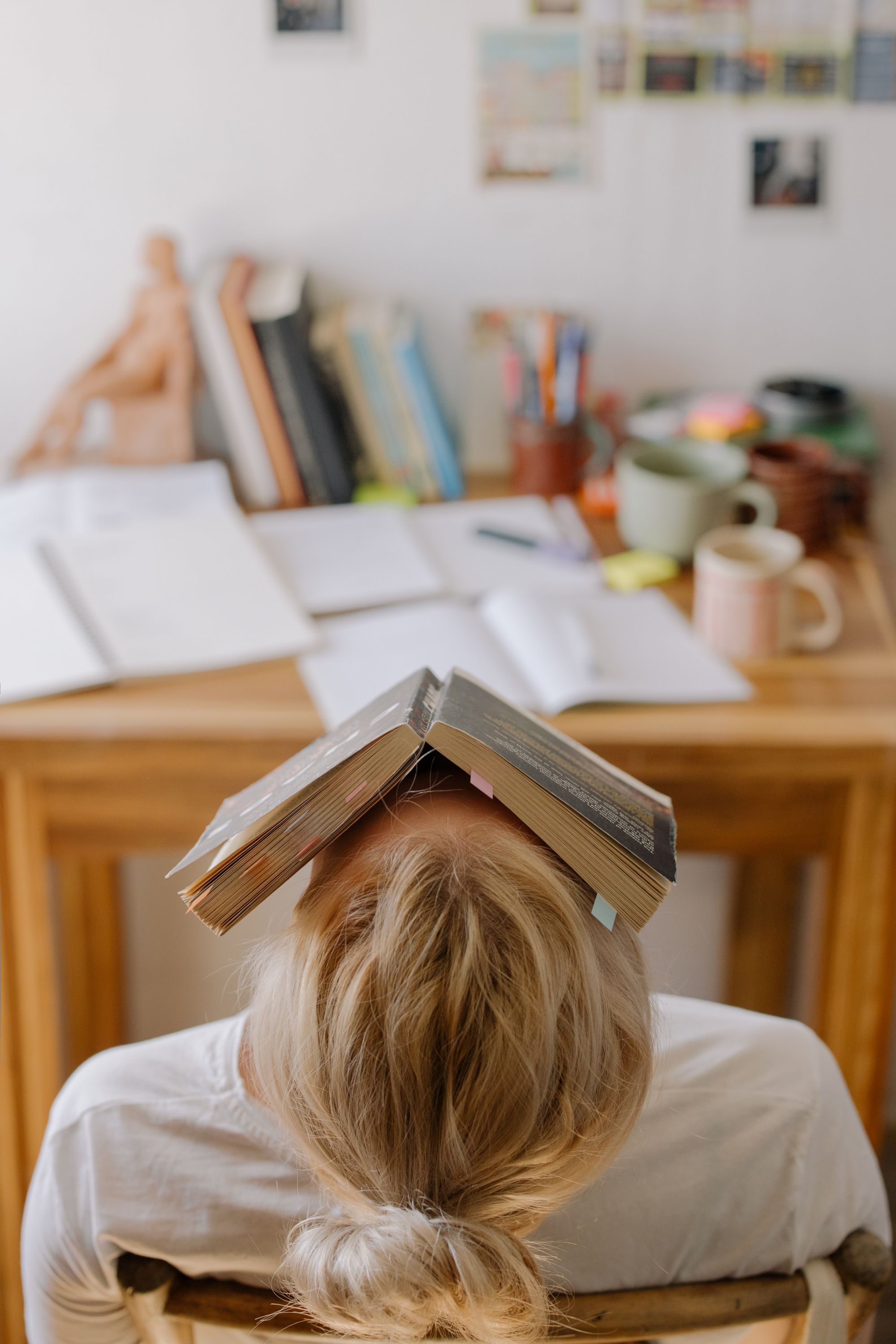 A girl with a book on top of her head, showing that she is exasperated.
