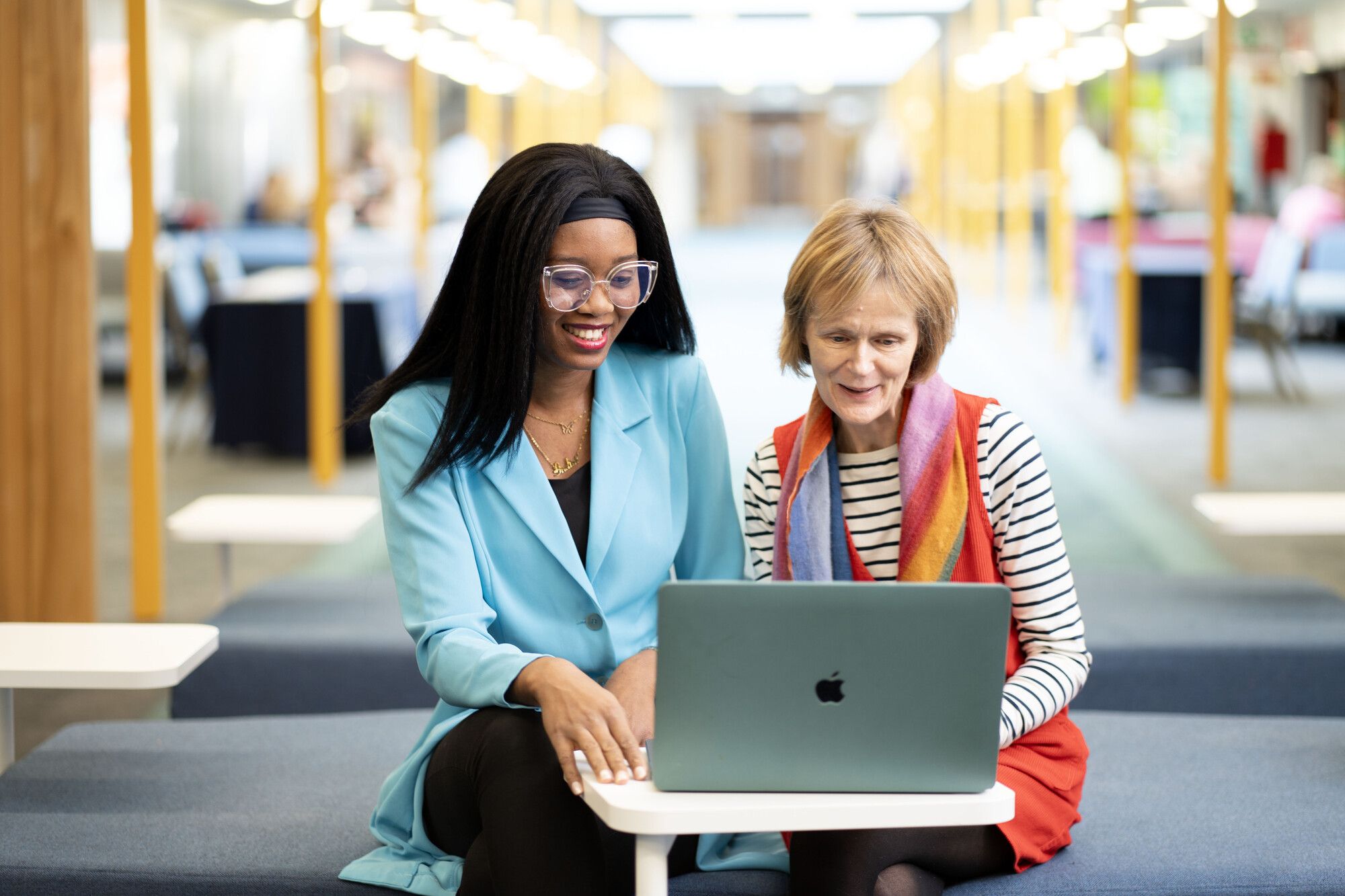 Student sitting next to Ulster University staff member. They are both looking at a laptop