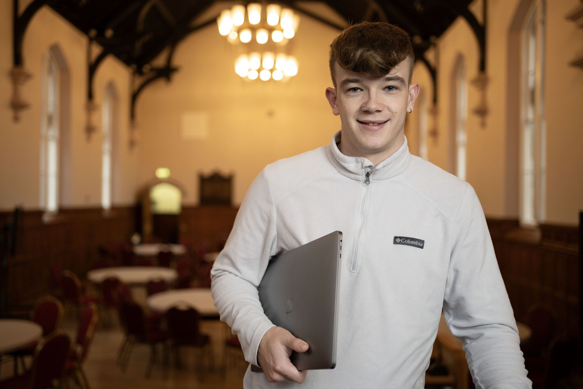 Male student holding a laptop under his arm